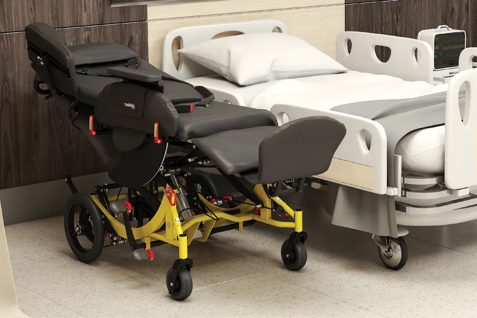 The Broda Traversa chair reclined flat alongside a hospital bed, ready for a transfer