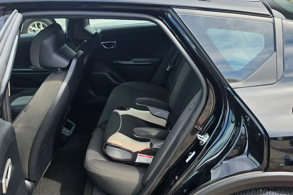 The rear seat of a black ReliaWheels sedan seen through the open back door