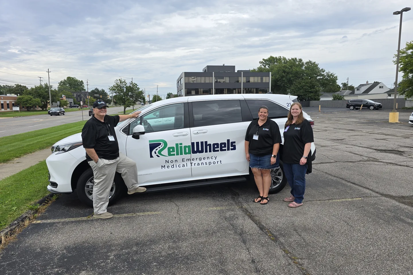 Three smiling ReliaWheels team members standing beside a branded wheelchair-accessible van