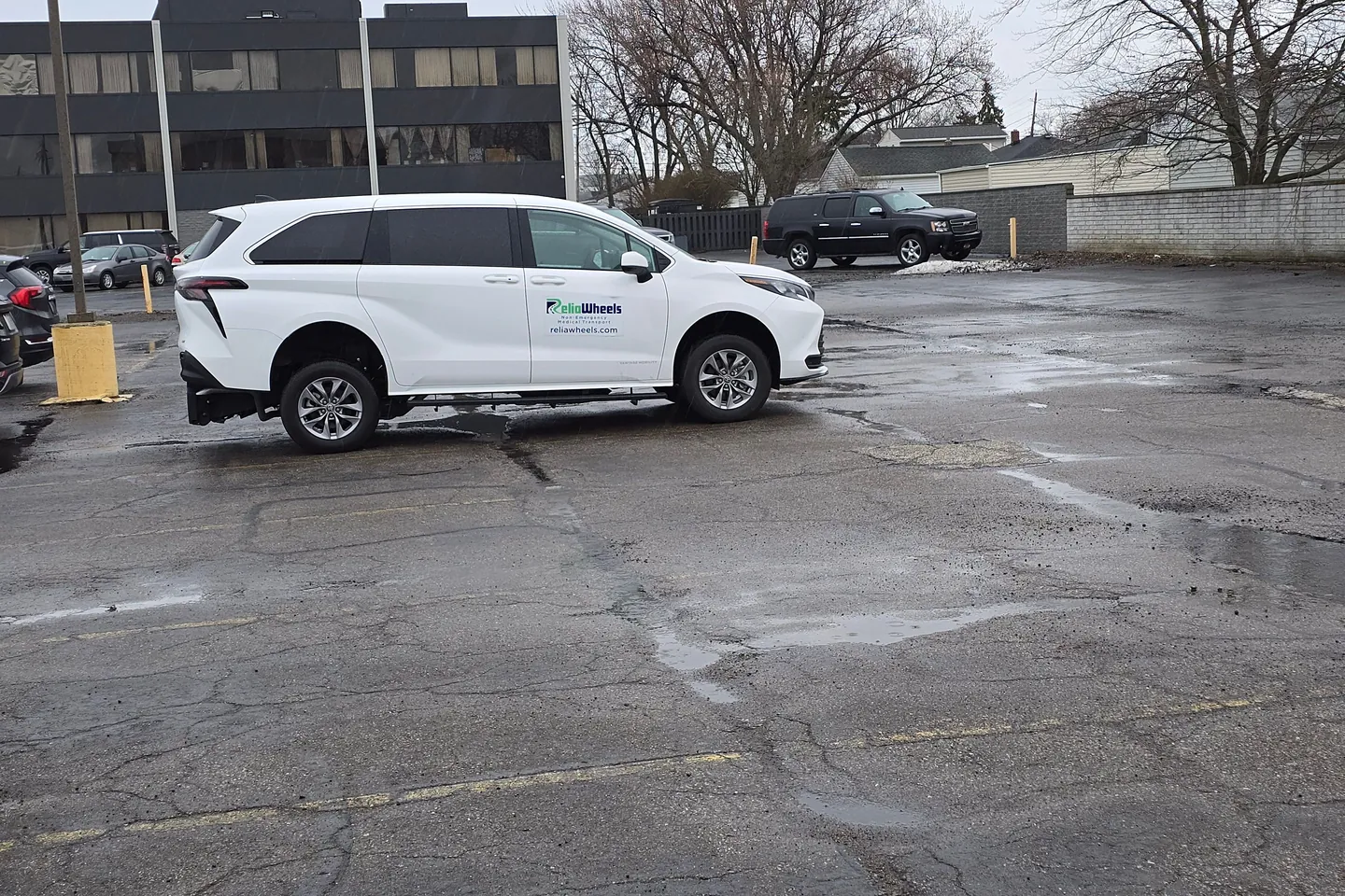 A white ReliaWheels wheelchair van parked in a wide city parking lot