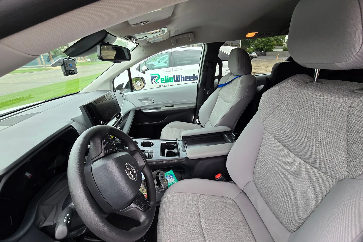 The driver's seat and dashboard of a ReliaWheels van, with a light gray interior