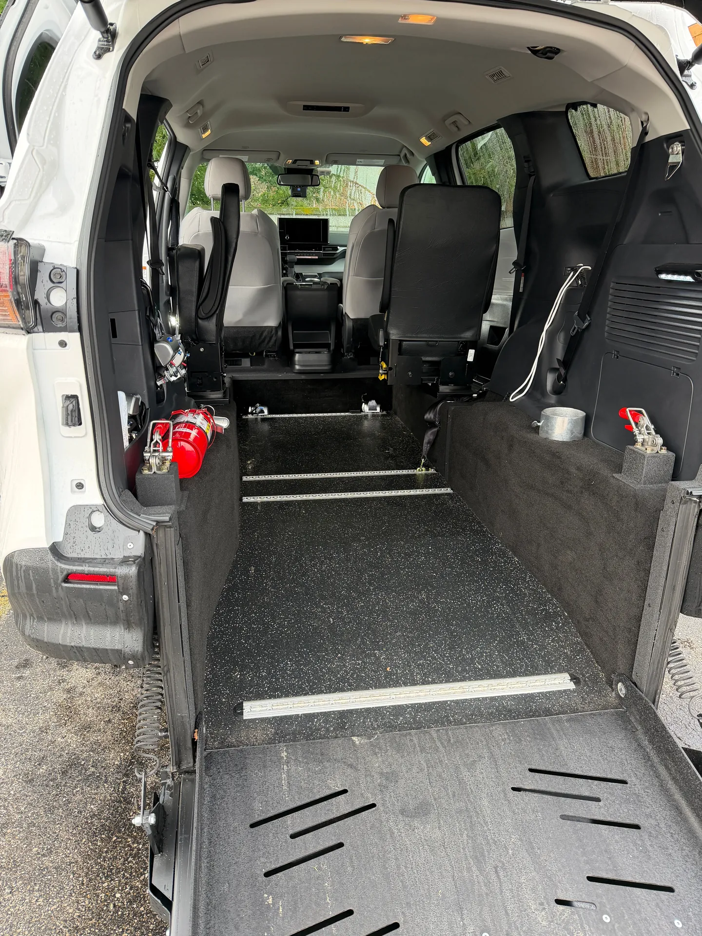 Inside a ReliaWheels wheelchair van: the securement floor track, lowered ramp and a fire extinguisher by the door