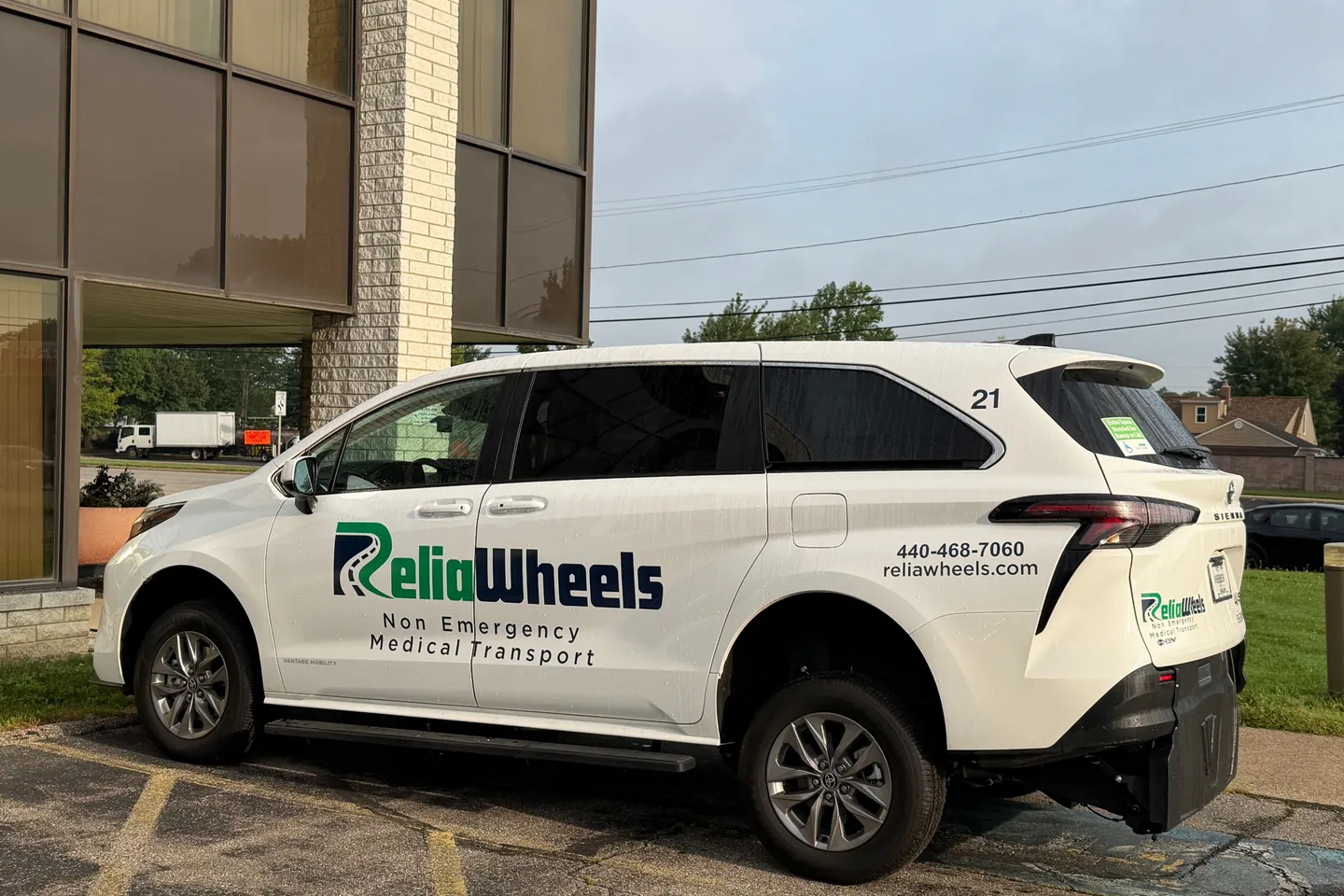 A white ReliaWheels wheelchair van parked outside an office building