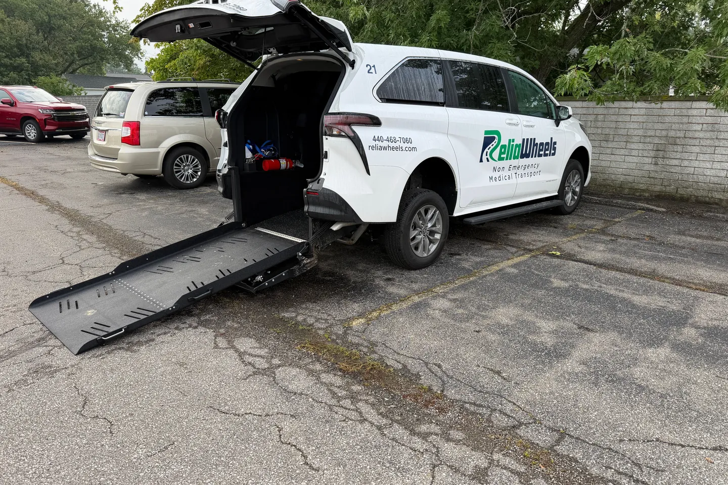 A ReliaWheels wheelchair van with its rear hatch open and the ramp lowered to the pavement